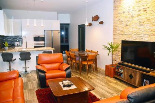 a living room with orange leather furniture and a kitchen at Breeze Apartments in Nadi