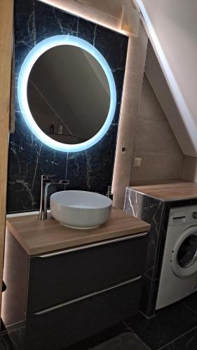 La salle de bains est pourvue d'un lavabo et d'un miroir rond. dans l'établissement Apartament Pod Brzyzkiem, à Leśnica