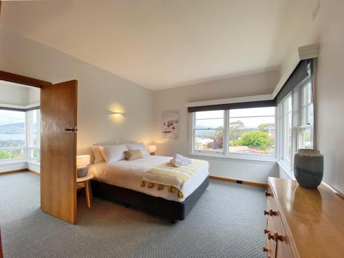 a bedroom with a bed and two windows at Bella Vista on Beach in Hobart