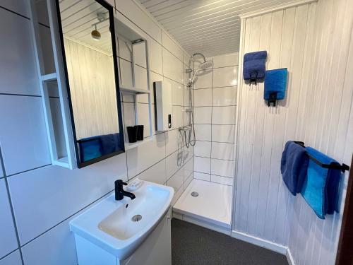 a white bathroom with a sink and a shower at Nurdachhäuschen Blaue Nordseewelle in Carolinensiel