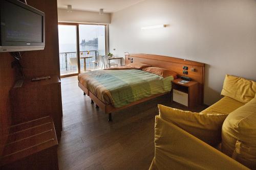 a bedroom with a bed and a tv and a couch at Ambienthotel Spiaggia in Malcesine