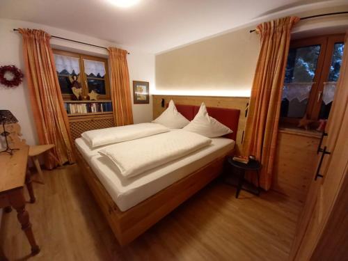 a bedroom with a bed with white sheets and a window at Ferienwohnungen Frick in Berchtesgaden