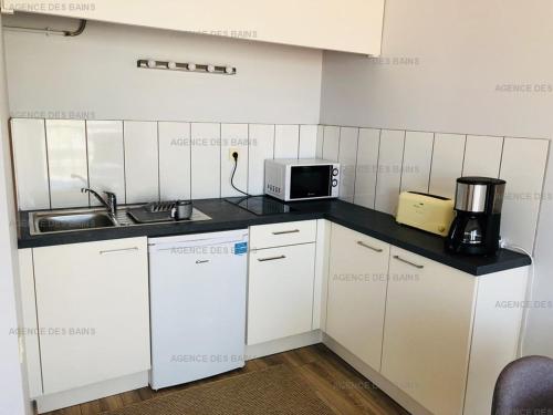 une petite cuisine avec un évier et un micro-ondes dans l'établissement Studio Cabine Renové à 200m de la Plage - Parking Privé - FR-1-433-37, à Arcachon