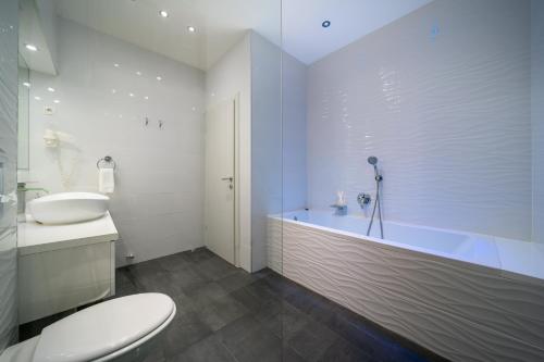 een badkamer met een bad, een toilet en een wastafel bij Villa Palladium in Makarska