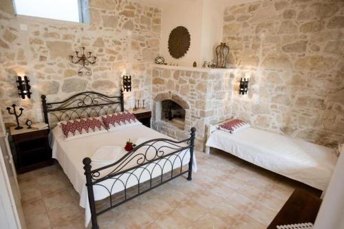 a bedroom with two beds and a stone wall at Traditional House 1 with Pool in Kamilari