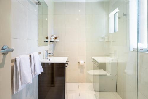 a white bathroom with a sink and a toilet at The Anchorage Bermagui in Bermagui