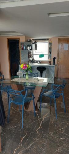 a kitchen with a table and two blue chairs at Apartamento de Cobertura frente para o mar Itapema in Itapema