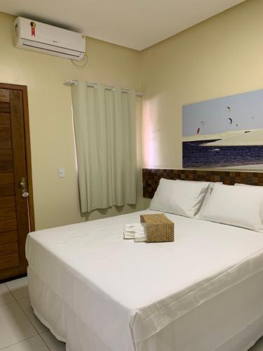 a bedroom with a large white bed with a fan at POUSADA DOS LAGOS in Paulino Neves