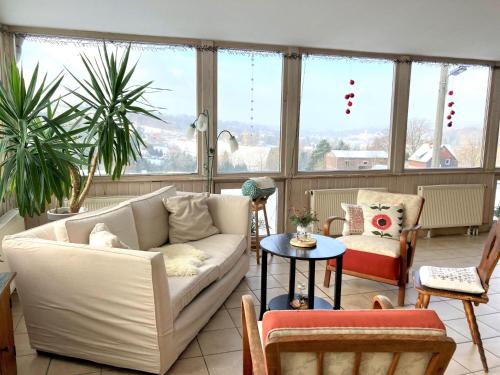 a living room with a couch and chairs and windows at Wohlfühlherberge Weitblick in Erlbach