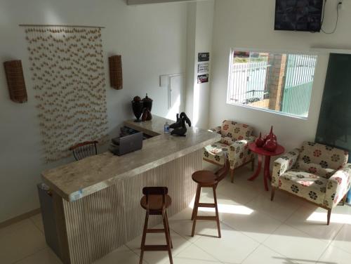 a kitchen with a counter and two chairs and a table at POUSADA DOS LAGOS in Paulino Neves