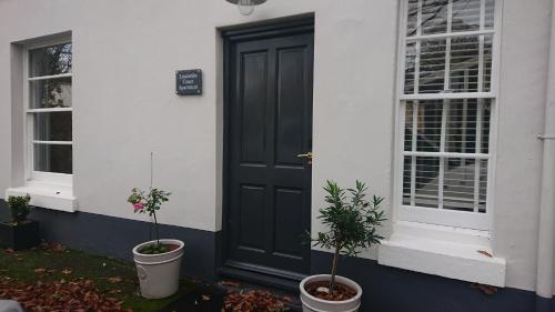 a black door and two potted plants in front of a house at Lincombe Court Apartment Wellswood Torquay in Torquay