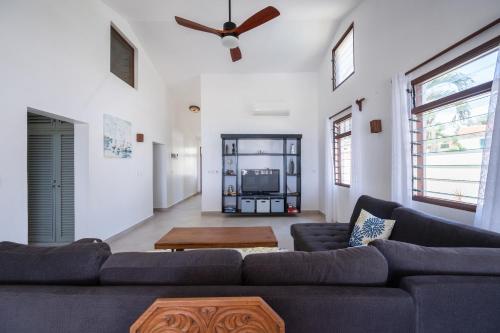 a living room with a couch and a ceiling fan at Oasys House - Beautiful Private Beach Front Home in Msambweni