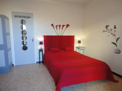 - une chambre dotée d'un lit rouge avec des draps rouges et des fleurs dans l'établissement Appartement tout confort avec terrasses, climatisation et parking privé à 300m de la plage - FR-1-229C-194, à Port-la-Nouvelle