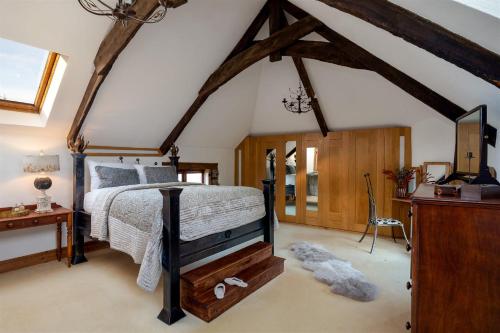 a bedroom with a bed in a room with beams at The Old Coach House - Converted barn with private garden parking and fireplace in Totnes