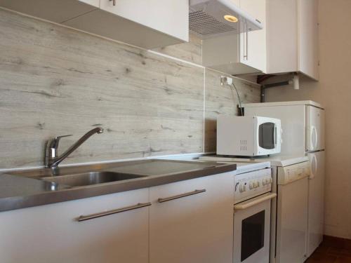 une cuisine blanche avec un évier et un micro-ondes dans l'établissement Appartement 2 pièces en front de mer, 4 couchages, parking privé, Port-la-Nouvelle - FR-1-229C-20, à Port-la-Nouvelle