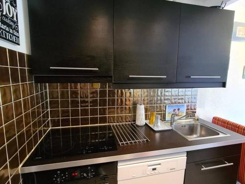 - une cuisine avec des placards noirs et un évier dans l'établissement Appartement T2 avec terrasse, jardinet, piscine et parking privé - Argelès-sur-Mer - FR-1-388-57, à Argelès-sur-Mer