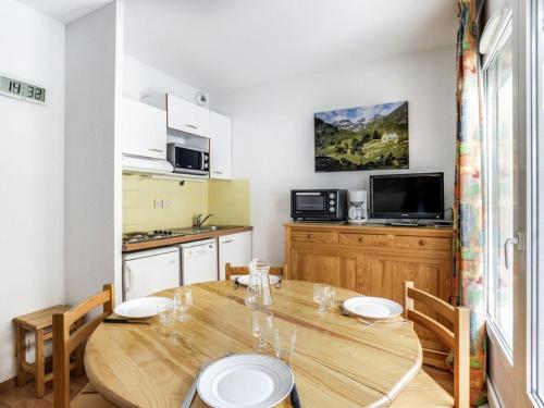 une cuisine et une salle à manger avec une table et des chaises en bois dans l'établissement Appartement cosy à Cauterets, 4 pers, balcon, proche centre et télécabine - FR-1-401-111, à Cauterets