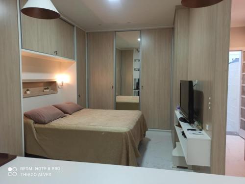 een kleine slaapkamer met een bed en een televisie bij Flat Residencial Simas in Florianópolis