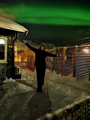 a woman standing in the snow with her arms outstretched at Aurora rooms in shared apartment nr2 We are doing privet Northen lights trips, reindeer trip and Fjord sommaroy trip in Tromsø