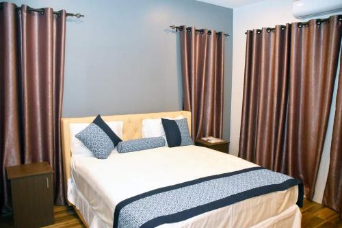 1 dormitorio con 1 cama con cortinas marrones en Breeze Apartments, en Nadi