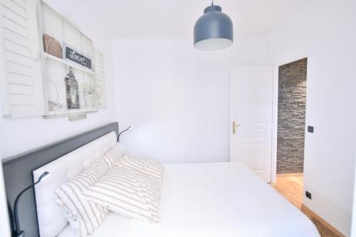 um quarto branco com uma cama e uma luz pendente em Paris La Villette - Charming Apartment 2 rooms em Paris