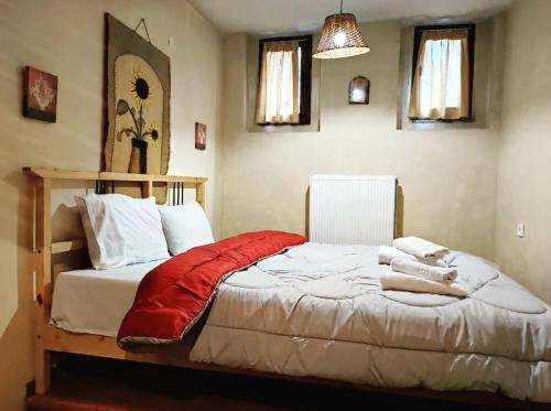 1 dormitorio con 1 cama con manta roja en Μaisonette Elpida, en Palaios Agios Athanasios