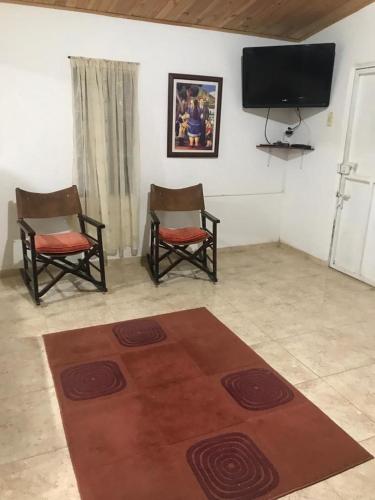 a living room with two chairs and a flat screen tv at La Isabela in Pitalito