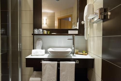 a bathroom with a sink and a shower with towels at Cottage Logis Hôtel - Restaurant in Dudelange