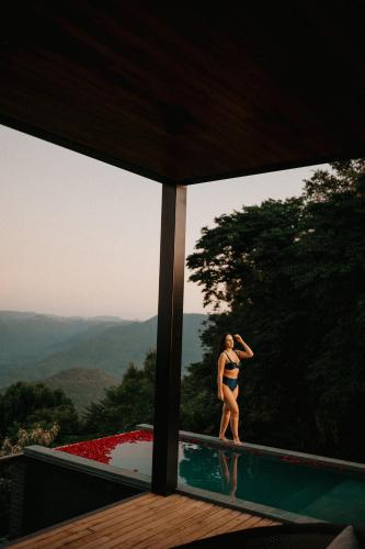 a woman in a bikini standing next to a swimming pool at Casas na montanha - Villa Montegrappa in Caxias do Sul