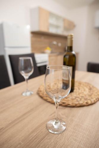 two wine glasses sitting on a table with a bottle of wine at Apartman Mirna Vinkovci in Vinkovci