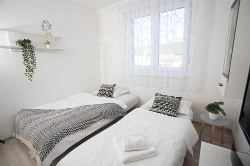2 camas en una habitación blanca con ventana en Apartman Mirna Vinkovci en Vinkovci