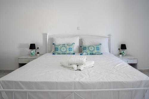 a white bed with white sheets and blue pillows at Pittas Studios in Kardamaina