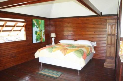 um quarto com uma cama numa parede de madeira em Raiatea Airport Bungalow em Uturoa