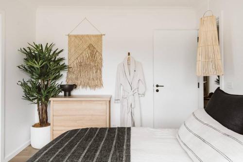 a bedroom with a bed and a plant and a door at The Lull Culburra in Culburra Beach