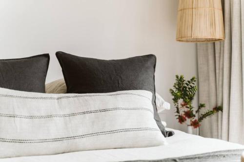 a bed with black and white pillows and a lamp at The Lull Culburra in Culburra Beach