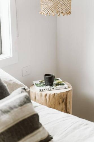a coffee cup sitting on a table next to a bed at The Lull Culburra in Culburra Beach