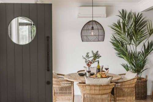 a dining room with a table and rattan chairs at The Lull Culburra in Culburra Beach