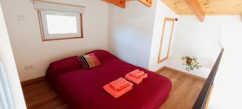 Cama roja en una habitación pequeña con ventana en Acogedora casa con increíble vista! en San Carlos de Bariloche