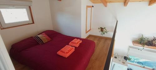 1 dormitorio con 1 cama roja y 2 toallas de color naranja en Acogedora casa con increíble vista! en San Carlos de Bariloche