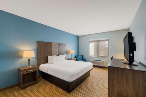 a hotel room with a bed and a flat screen tv at Best Western South Plains Inn & Suites in Levelland