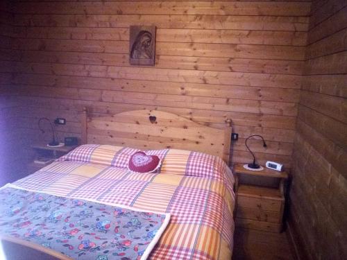 ein Schlafzimmer mit einem Bett in einer Holzwand in der Unterkunft La Casa Rossa - Presolana in Castione della Presolana