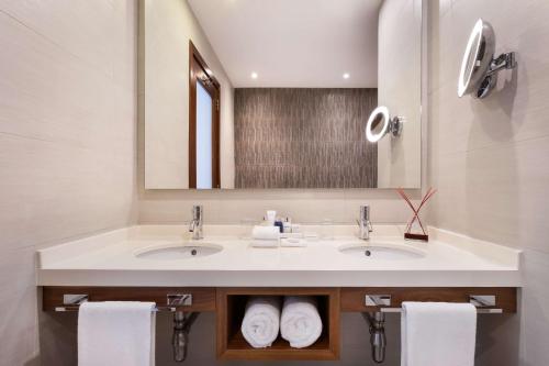 a bathroom with two sinks and a mirror and towels at Radisson Blu Resort, Malta St. Julian's in St Julian's