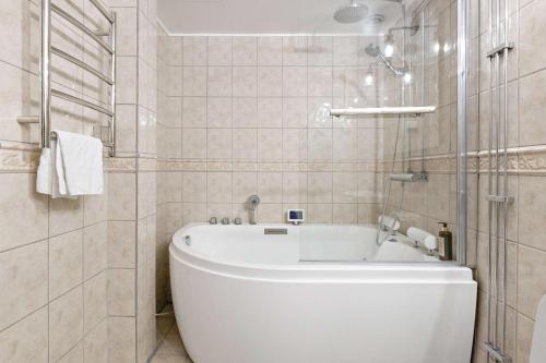 a white bath tub in a bathroom with tiles at Nora Stadshotell, Sure Hotel Collection by Best Western in Nora