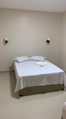 una camera con un letto bianco con due cuscini di Encanto da Vila a Morro de São Paulo