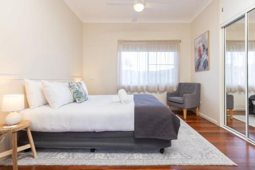 a bedroom with a large bed and a chair at Jasmine Apartment in Forster