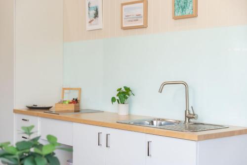 uma cozinha com armários brancos e um lavatório em Jasmine Apartment em Forster