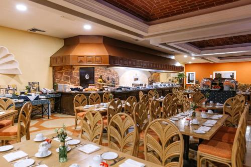 a restaurant with wooden tables and chairs and a kitchen at Holiday Inn Merida by IHG in Mérida