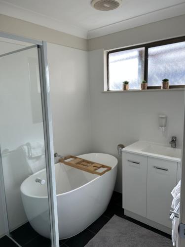 uma casa de banho branca com uma banheira e um lavatório em Beautiful and comfy 3 bedrooms duplex close to everything em Budgewoi