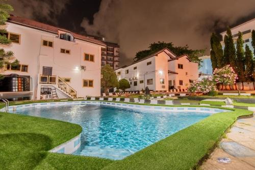 uma piscina em frente a alguns edifícios à noite em The Winford Boutique Hotel Airport em Acra