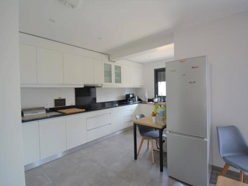 - une cuisine avec des placards blancs, une table et un réfrigérateur dans l'établissement Villa 4 Suites avec Spa de Nage, Terrasse et Clim - Proche Centre Ruoms - FR-1-382-149, à Ruoms